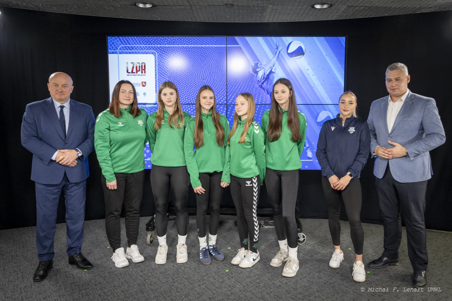 Marszałek Jarosław Stawiarski i Tomasz Lewtak prezes Lubelskiego Związku Piłki Ręcznej oraz kilka dziewcząt z drużyny pozują wspólnie do zdjęcia