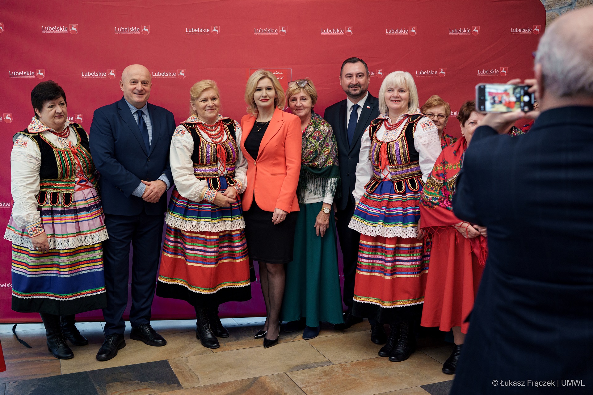 Marszałek Jarosław Stawiarski, wicemarszałek Marek Wojciechowski, dyrektor Ewa Szałachwiej pozują do zdjęcia wspólnie z kilkoma paniami ubranymi w stroje ludowe
