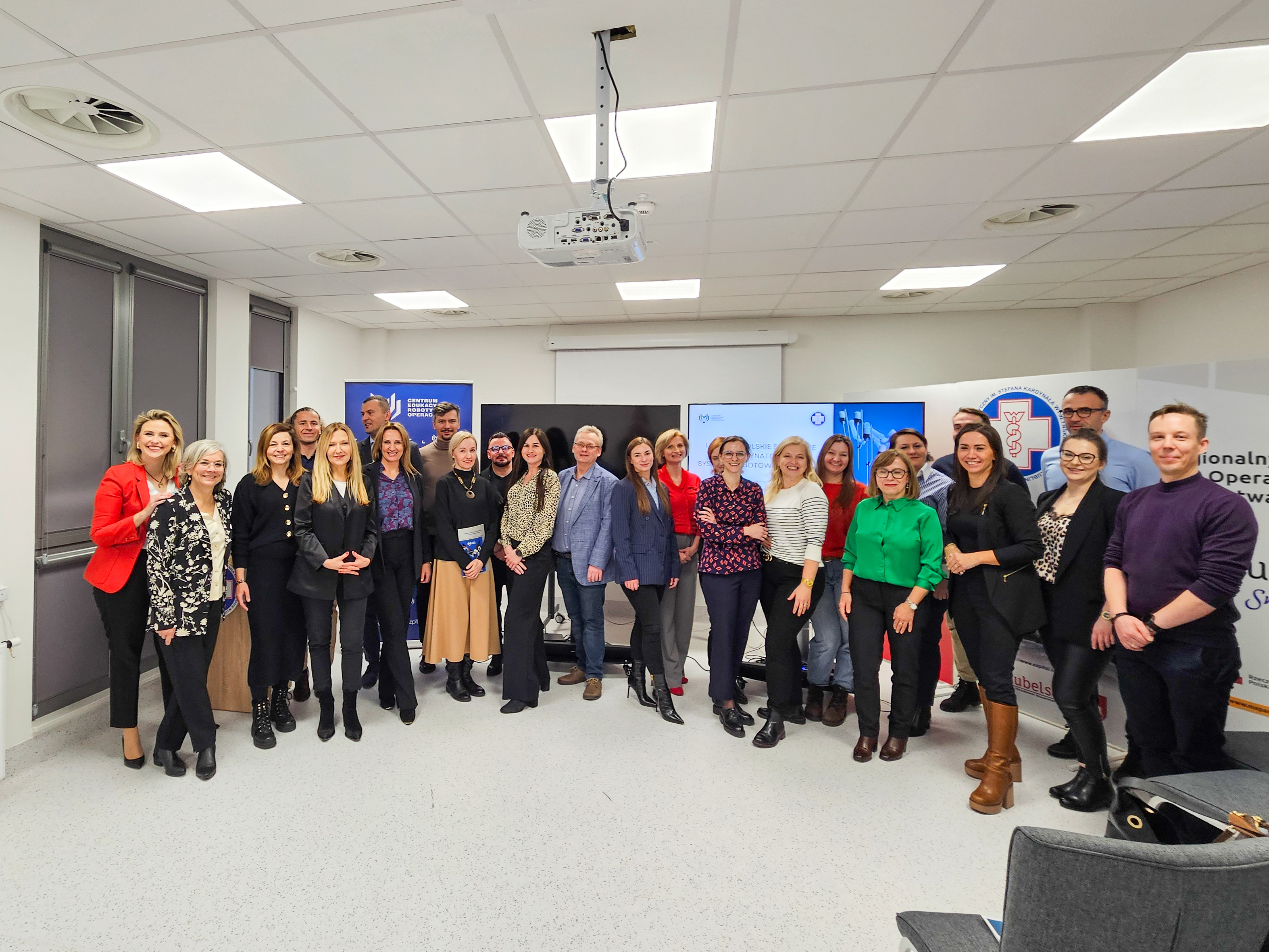 W sali konferencyjnej pozuje do zdjęcia około dwudziestu osób
