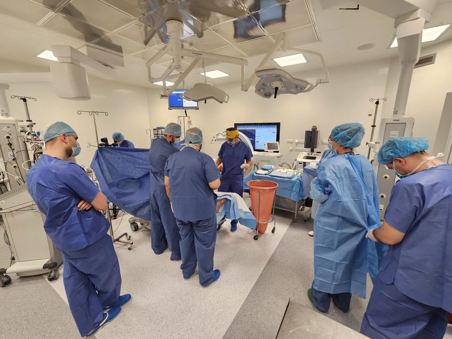 Kilku chirurgów w fartuchach podczas zabiegu na sali operacyjnej