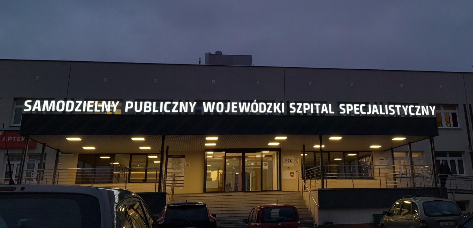 Budynek szpitala noca z oświetlonym napisem