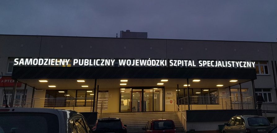 Budynek szpitala noca z oświetlonym napisem
