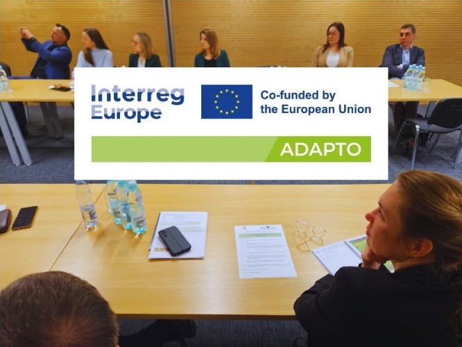 Logo projektu na tle zdjęcia sali z siedzącymi uczestnikami