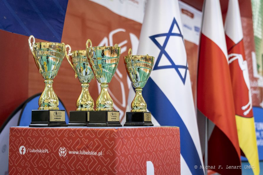 Puchary ustawione na podeście na sali gimnastycznej