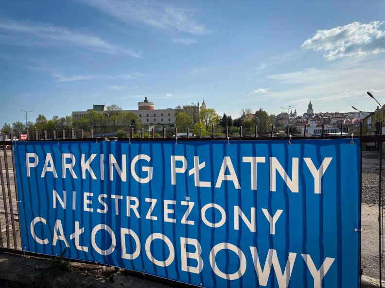 Baner z napisem Parking Płatny Niestrzeżony Całodobowy