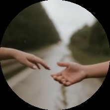 Dwoje rąk sięga do siebie na tle drogi