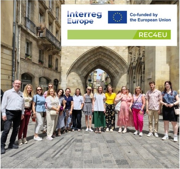 Partnerzy projektu stoją przed historyczną bramą w Bordeaux, tworząc półkole. W prawym górnym rogu jest logo projektu.