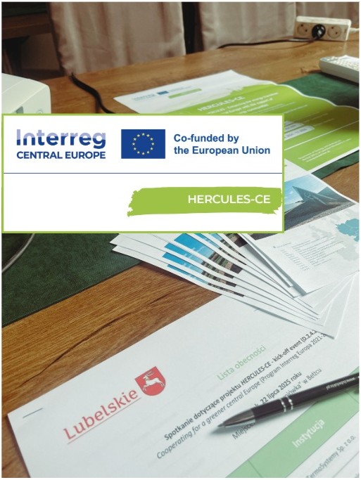 Biurko z wyłożonymi ulotkami, plakatami promocyjnymi i listą obecności, wykorzystywane podczas spotkania.