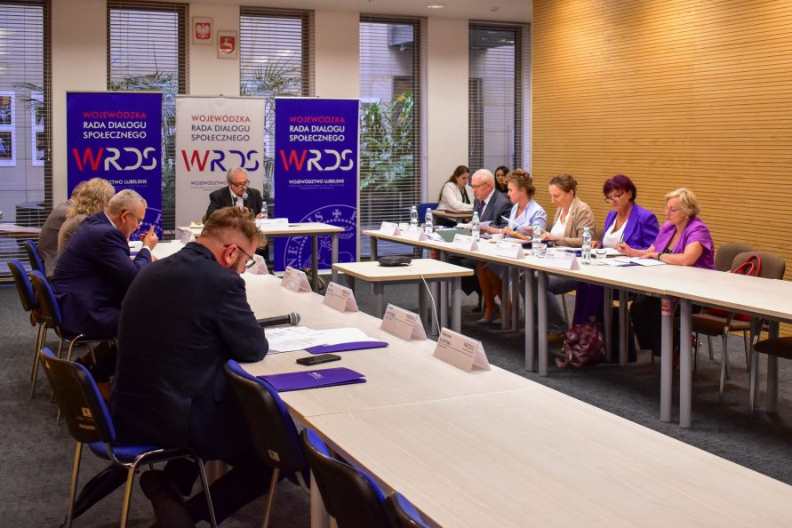 Zdjęcie z posiedzenia SZR ds. Polityki Społecznej i Ochrony Zdrowia Wojewódzkiej Rady Dialogu Społecznego. Uczestnicy spotkania w trakcie rozmowy przy stołach.