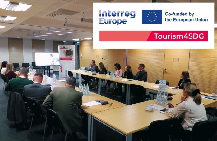 Interesariusze siedzą przy stole ułożonym w prostokątną podkowę.