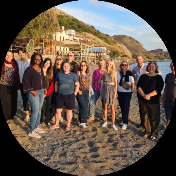 partnerzy ADAPTO na brzegu Morza Egejskiego. Widać promienie Słońca oraz fragment plaży.