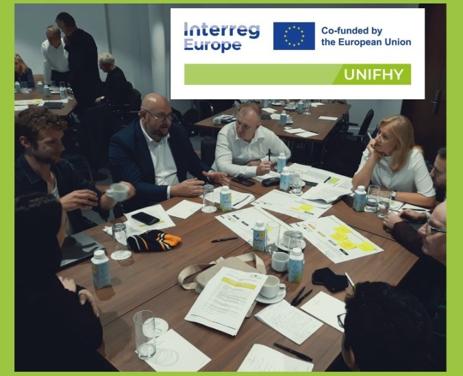 Uczestnicy, w tym przedstawiciel Województwa, siedzą przy stole pośród notatek.