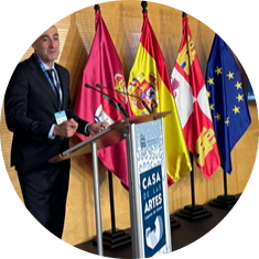 Uczestnik spotkania daje prezentację. W tle flagi związane z partnerstwem.