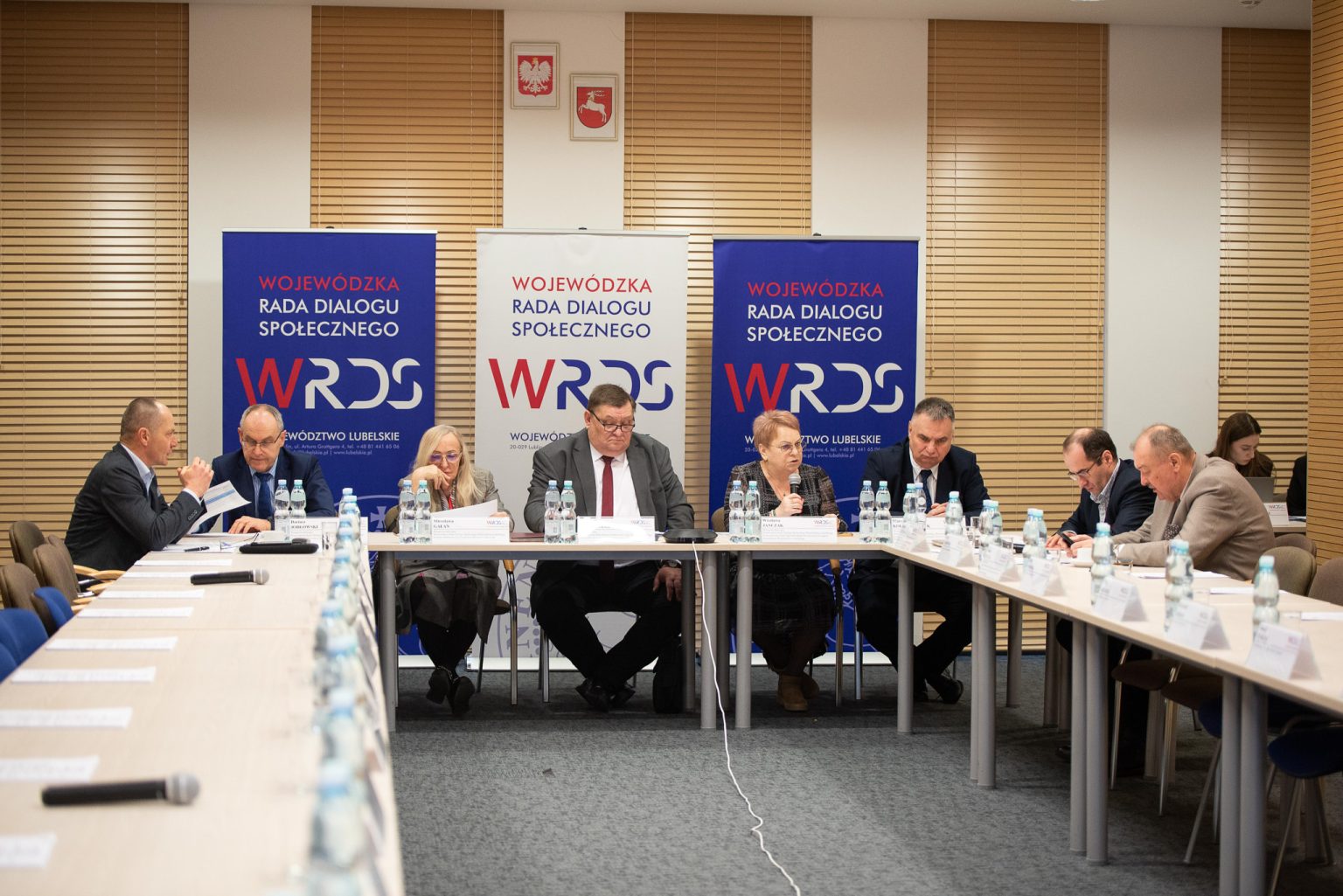 Członkowie Prezydium Wojewódzkiej Rady Dialogu Społecznego Województwa Lubelskiego siedzą wokół stołu w kształcie litery U, obradują podczas posiedzenia Prezydium