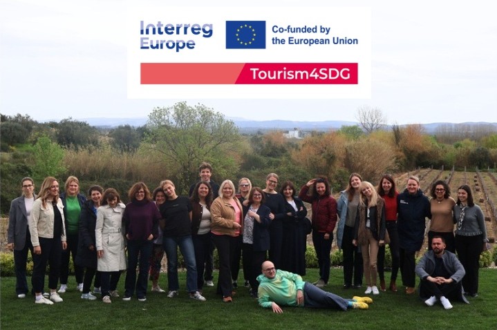 Partnerzy projektu pozują w plenerze podczas wizyty studyjnej. W tle, na widnokręgu, widać pas krzaków i zieleni.