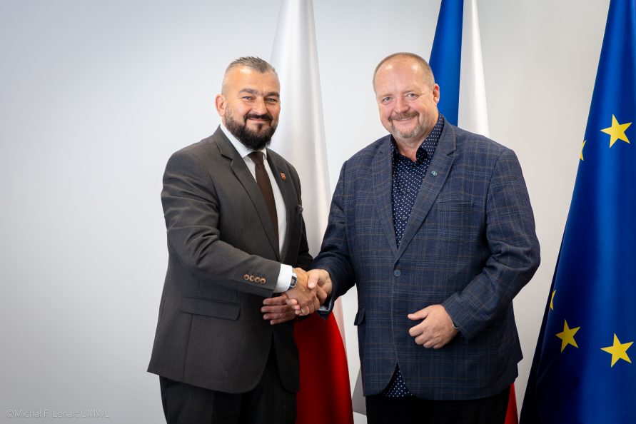 Marszałek Stawiarski pozuje do wspólnego zdjęcia z beneficjentem. W tle mury zamku.