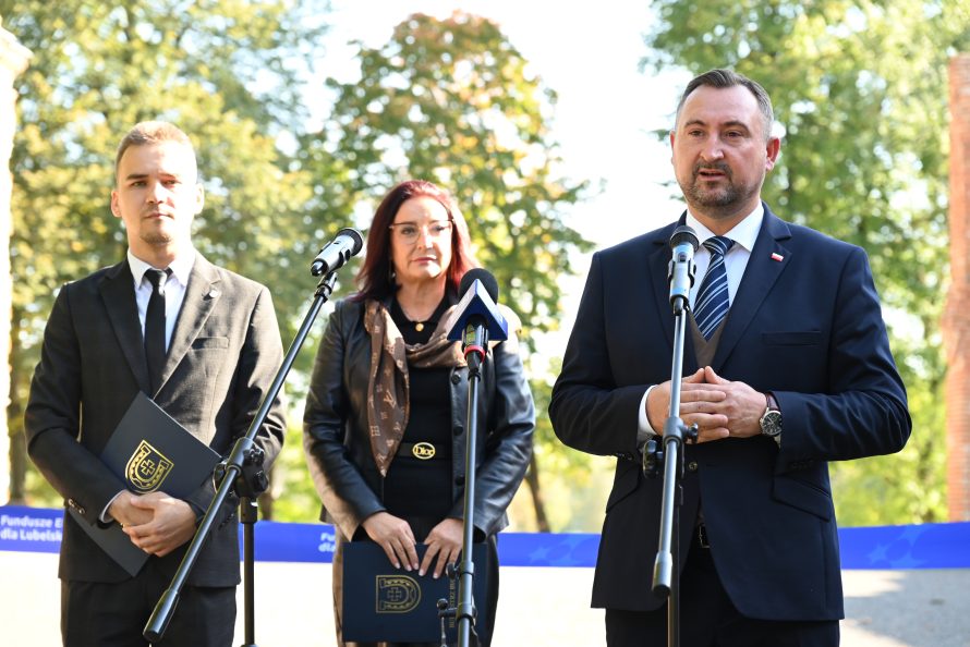 Wicemarszałek Wojciechowski przemawia na konferencji. Towarzyszą mu dwie osoby po jego prawej.